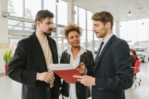 Les professionnels des entreprises discutent d'un contrat de location de voiture ou d'achat dans un cadre de salle d'exposition.