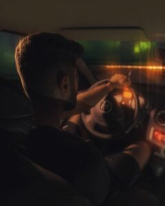 un homme assis dans une voiture tenant un volant